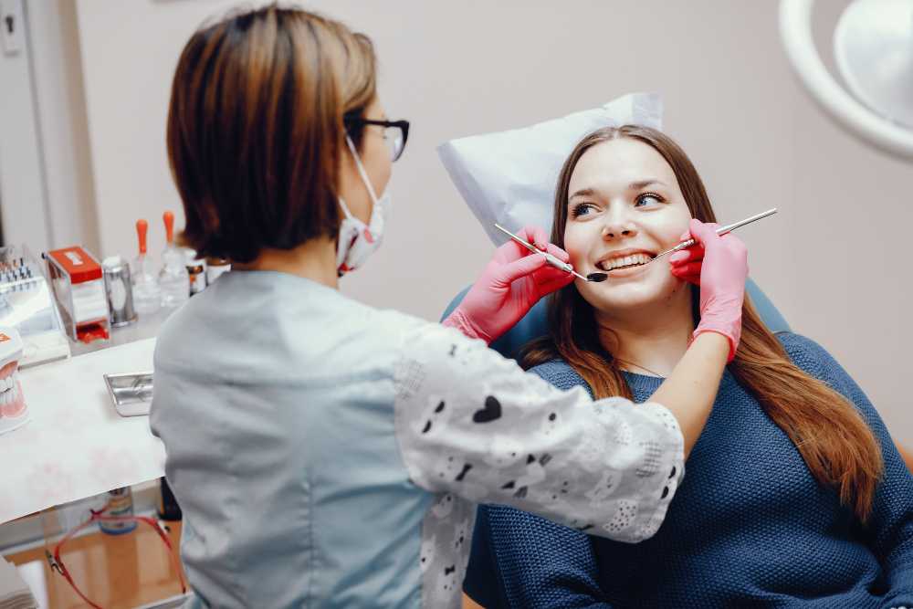 A dentist checks a woman's teeth, highlighting the process of root canal therapy during the dental examination.