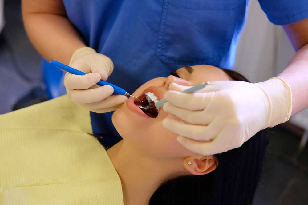 A dentist performing a teeth cleaning on a woman, emphasizing routine dental care and tooth extractions.