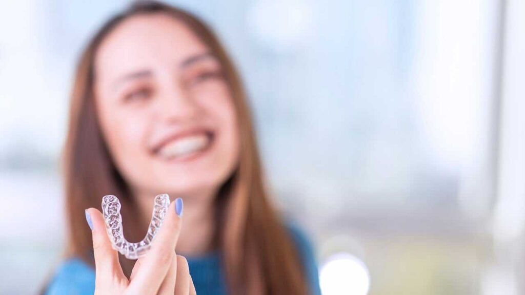 A smiling woman proudly holds a toothbrush promoting dental health and the benefits of dental implants