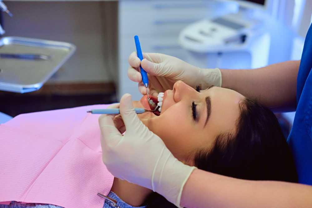 A woman undergoing a teeth cleaning session with a dentist, highlighting cavity repair efforts.