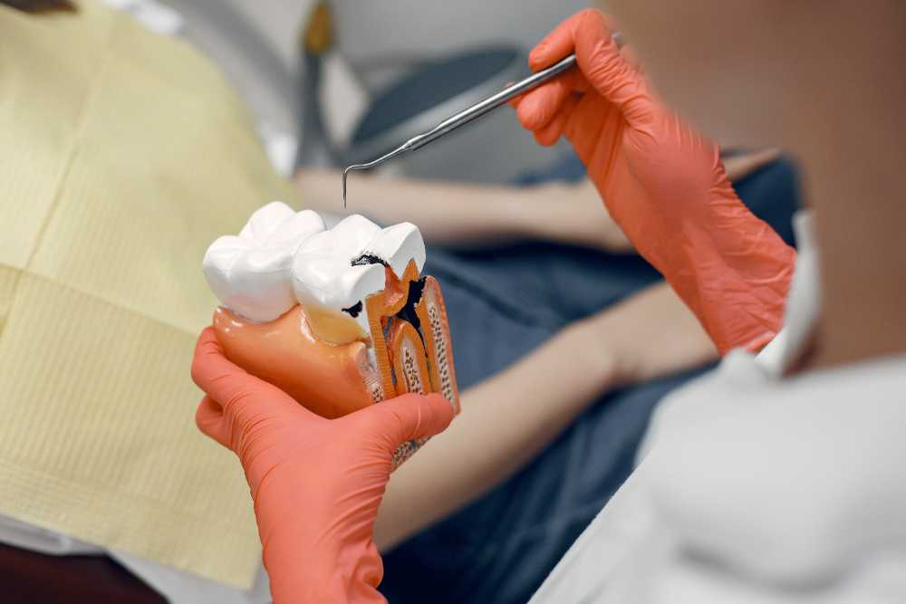 A person sits in a dentist chair, holding a toothbrush, preparing for inlays and onlays treatment.