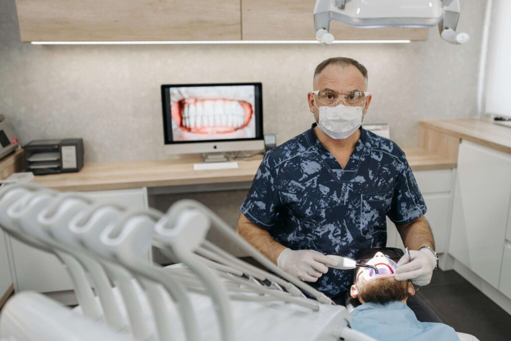 A dentist examines a patient in a dental office, focusing on oral surgery procedures and patient care.