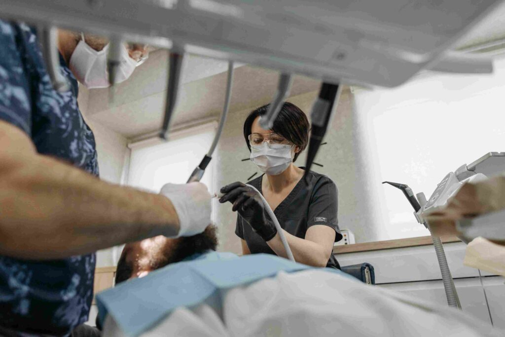 A dentist inspects a patient's teeth, focusing on oral health in a maxillofacial surgery environment.