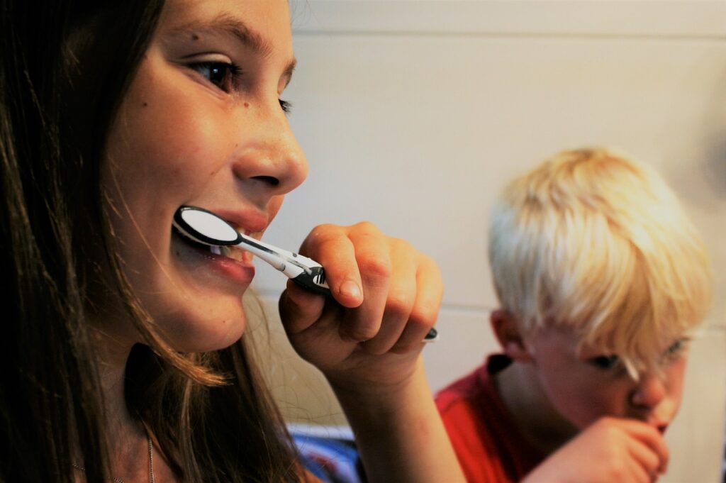 A young girl brushing her teeth, showcasing the importance of dental hygiene and the use of sealants for protection.