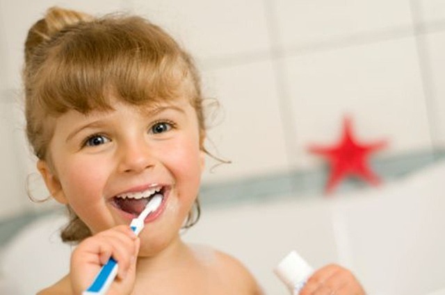 A young girl brushes her teeth in the bathroom, promoting good dental hygiene to prevent tooth decay.