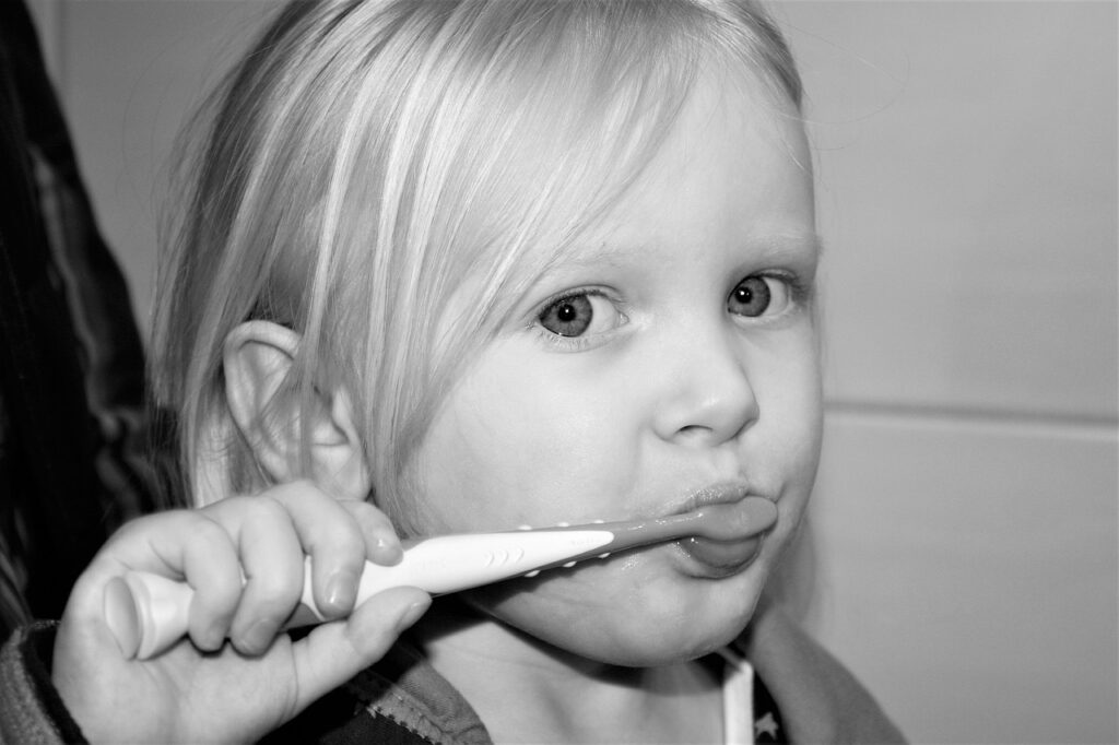 A little girl brushes her teeth, emphasizing the importance of oral care in preventing cavities.