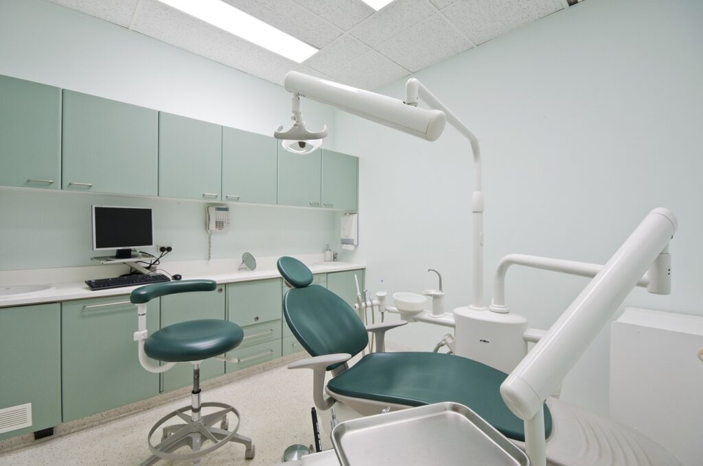 A dental room featuring green cabinets and a chair, designed for orthodontic care for children.