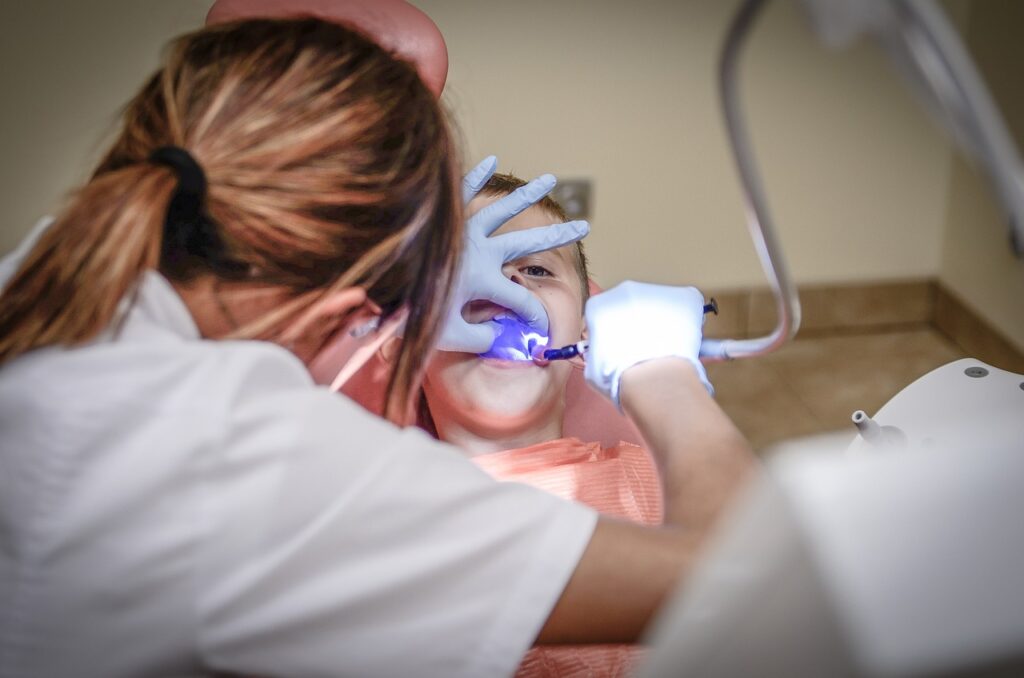 A woman receiving a dental cleaning from a dentist, highlighting the importance of oral health and pediatric dentistry costs.